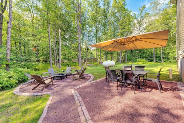 An outdoor patio with a table and chairs, surrounded by a gravel path and lush greenery.