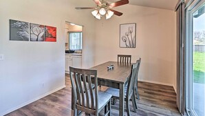A dining area with a wooden table and chairs, a ceiling fan, and artwork on the walls.
