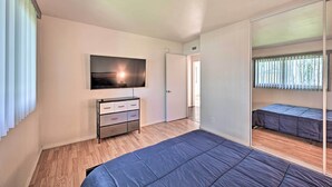 A bedroom with a bed, a TV, a dresser, and a large mirror.