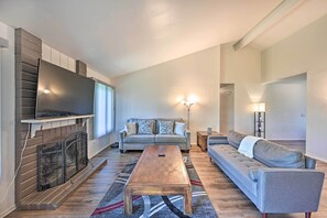 A living room with a fireplace, a sofa, a coffee table, and a television. - Family-friendly Oceanside Home: 5 Mi to Beach (Oceanside)