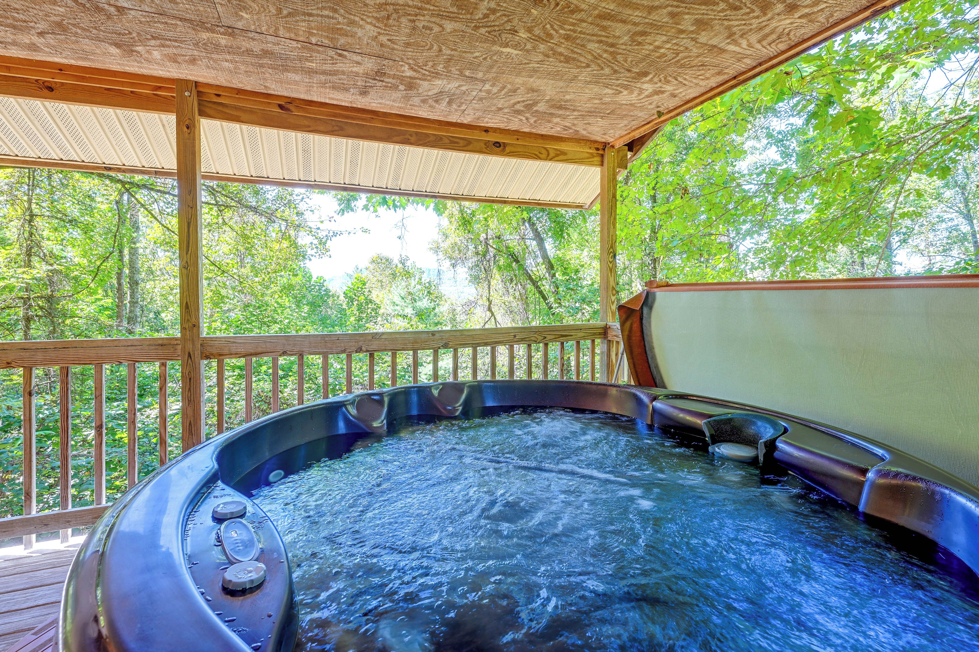 Ein Whirlpool auf einer Holzterrasse mit Blick auf Bäume.