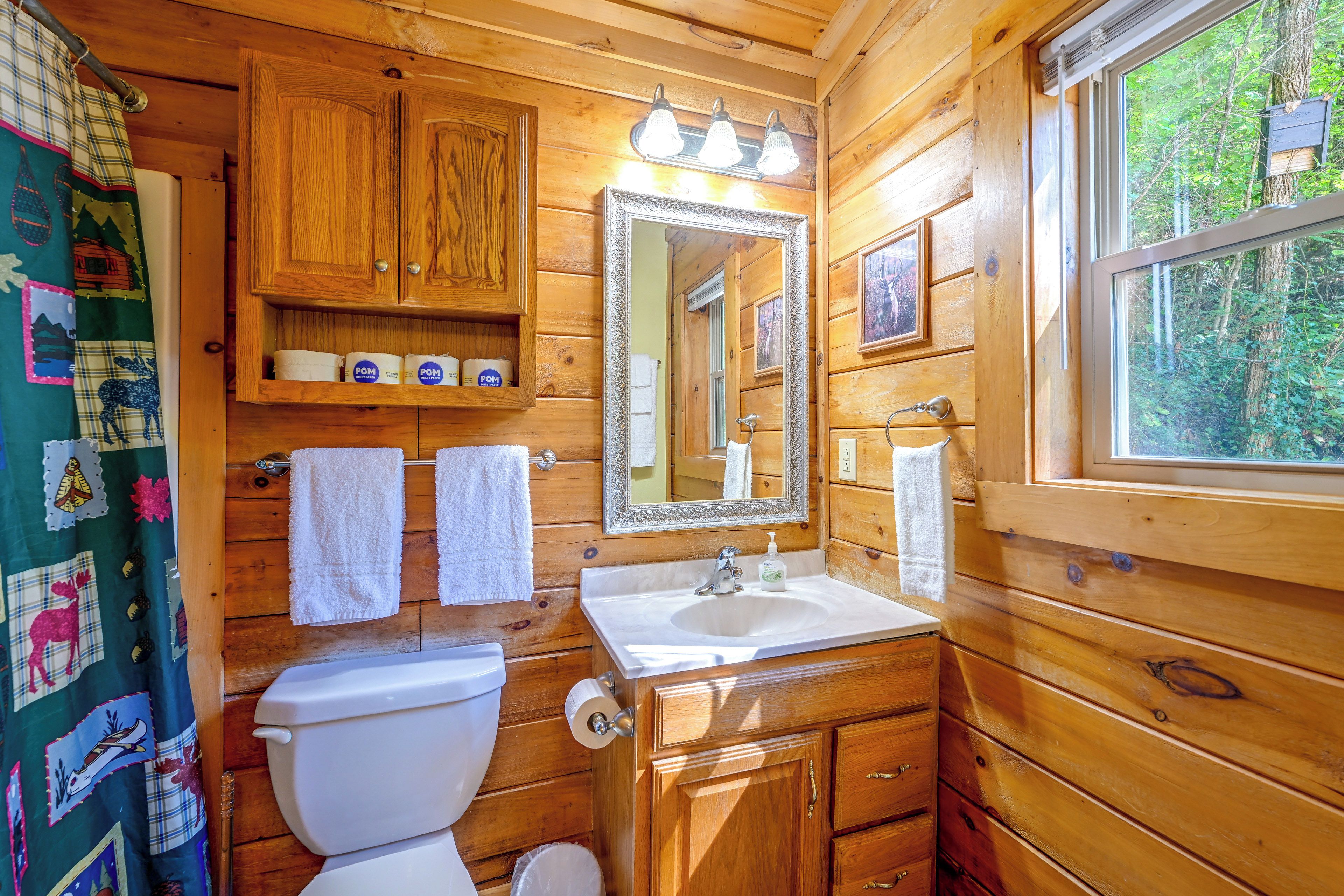 A wooden cabin bathroom with a toilet, sink, and mirror.