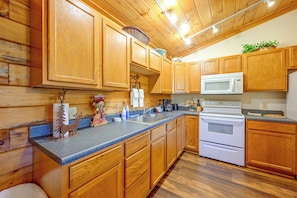 A kitchen with wooden cabinets, a granite countertop, a microwave, and a stove. - Cozy Deer Glen' Cabin w/ Private Hot Tub & Porch! (Bryson City)