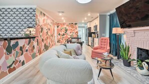 A modern living room with a sectional sofa, a fireplace, and a kitchen in the background. - Eclectic Atlanta Abode < 3 Mi to Downtown! (Atlanta)