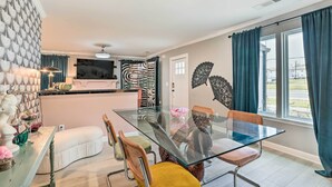 A modern dining area with a glass table, cushioned chairs, and a decorative wall. - Eclectic Atlanta Abode < 3 Mi to Downtown! (Atlanta)