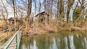 A wooden bridge over a calm river, surrounded by trees and a small building. - Cozy Heber Springs Cabin w/ Deck & Dock! (Heber Springs)
