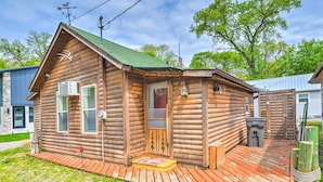 A log cabin with a green roof, a wooden deck, and a small porch. - Historic Cabin Retreat: Steps to Okoboji Lake (Arnolds Park)