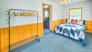 A bedroom with a bed, wooden paneling, a ceiling fan, and a window. - Historic Cabin Retreat: Steps to Okoboji Lake (Arnolds Park)