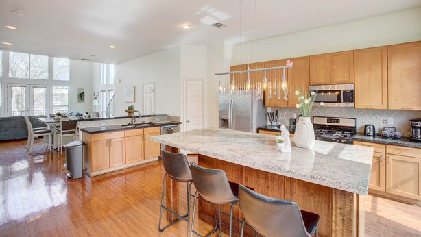 A spacious kitchen with wooden cabinets, a large island, bar stools, and modern appliances.