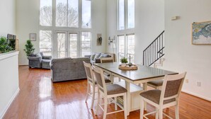 A spacious living area with a dining table, multiple chairs, a sofa, and a staircase leading to an upper level.