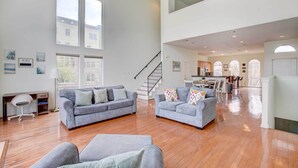 A spacious living area with two grey sofas, a wooden floor, and a staircase leading to an upper level.