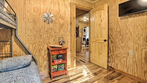 A wooden interior with a bunk bed, a small shelf with board games, and a laundry area in the background.