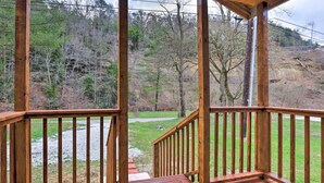 A wooden deck with a view of a grassy area and trees.
