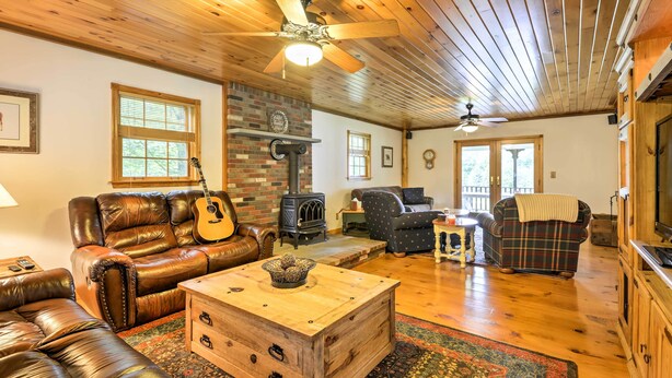 A cozy living room with leather sofas, a wooden coffee table, a fireplace, and a ceiling fan. - Thompson Home w/ Deck + Pond, 8 Mi to Elk Mountain (Thompson)