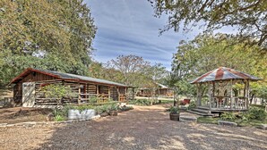 A rustic cabin with a wooden exterior, surrounded by a gravel path and potted plants. - 'gruene Cabin' - Pet Friendly New Braunfels Studio (New Braunfels)
