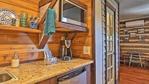 A kitchen with wooden walls, a microwave, a sink, and a dishwasher. - 'gruene Cabin' - Pet Friendly New Braunfels Studio (New Braunfels)