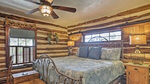 A rustic bedroom with a wooden bed, a desk, and a chair. - 'gruene Cabin' - Pet Friendly New Braunfels Studio (New Braunfels)