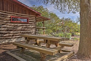 Uma cabana rústica de toras com uma mesa de piquenique em frente.