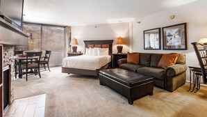 A spacious bedroom with a large bed, a sofa, and a dining area.