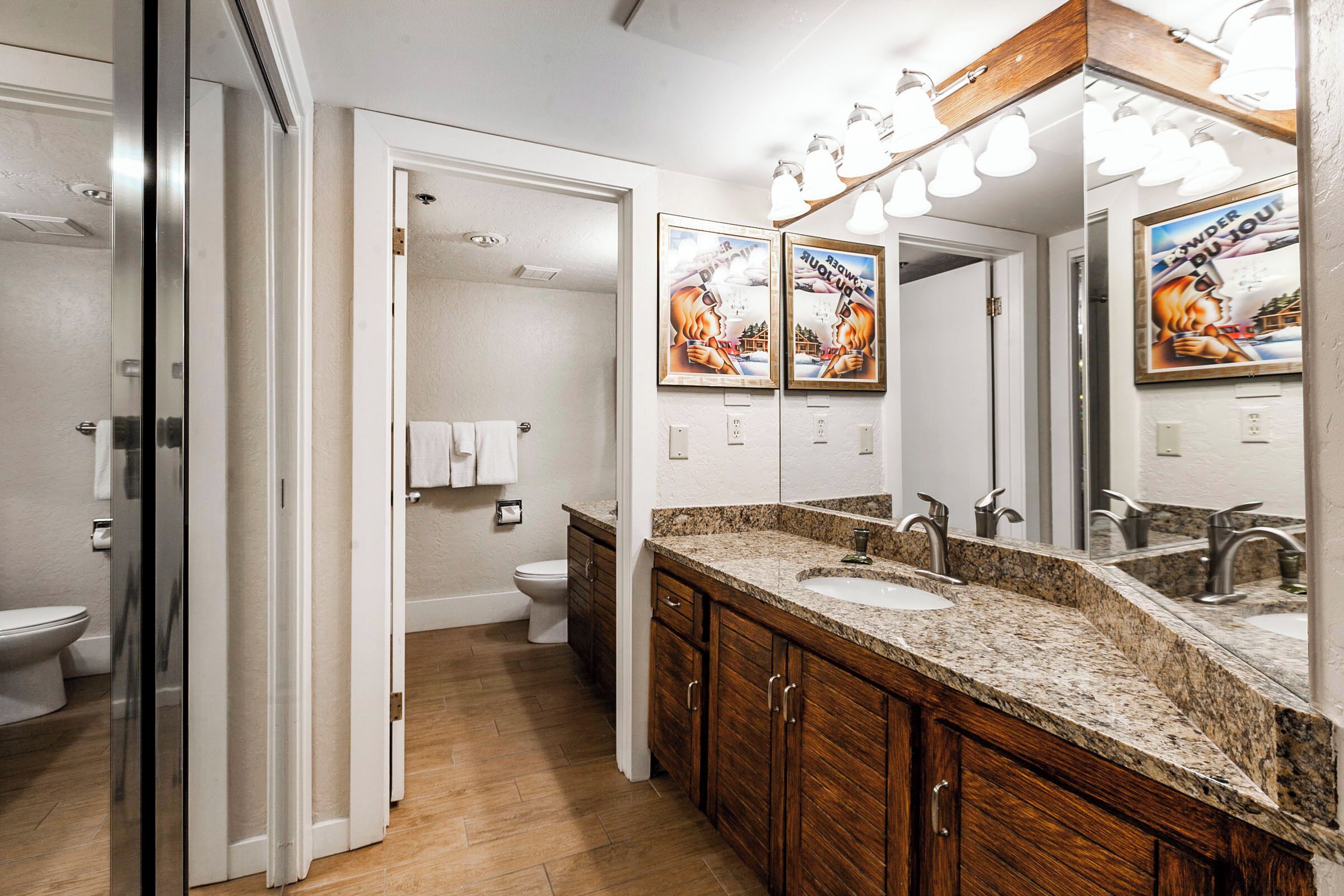Une salle de bain avec un meuble-lavabo en bois, un grand miroir et un espace douche.