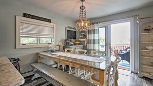 A dining area with a chandelier, a table with chairs, a bench, a window with blinds, and a view of the outdoors.