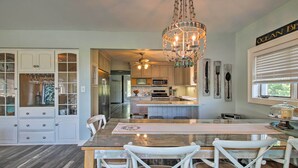 A spacious kitchen with a central island, white cabinetry, and a chandelier.