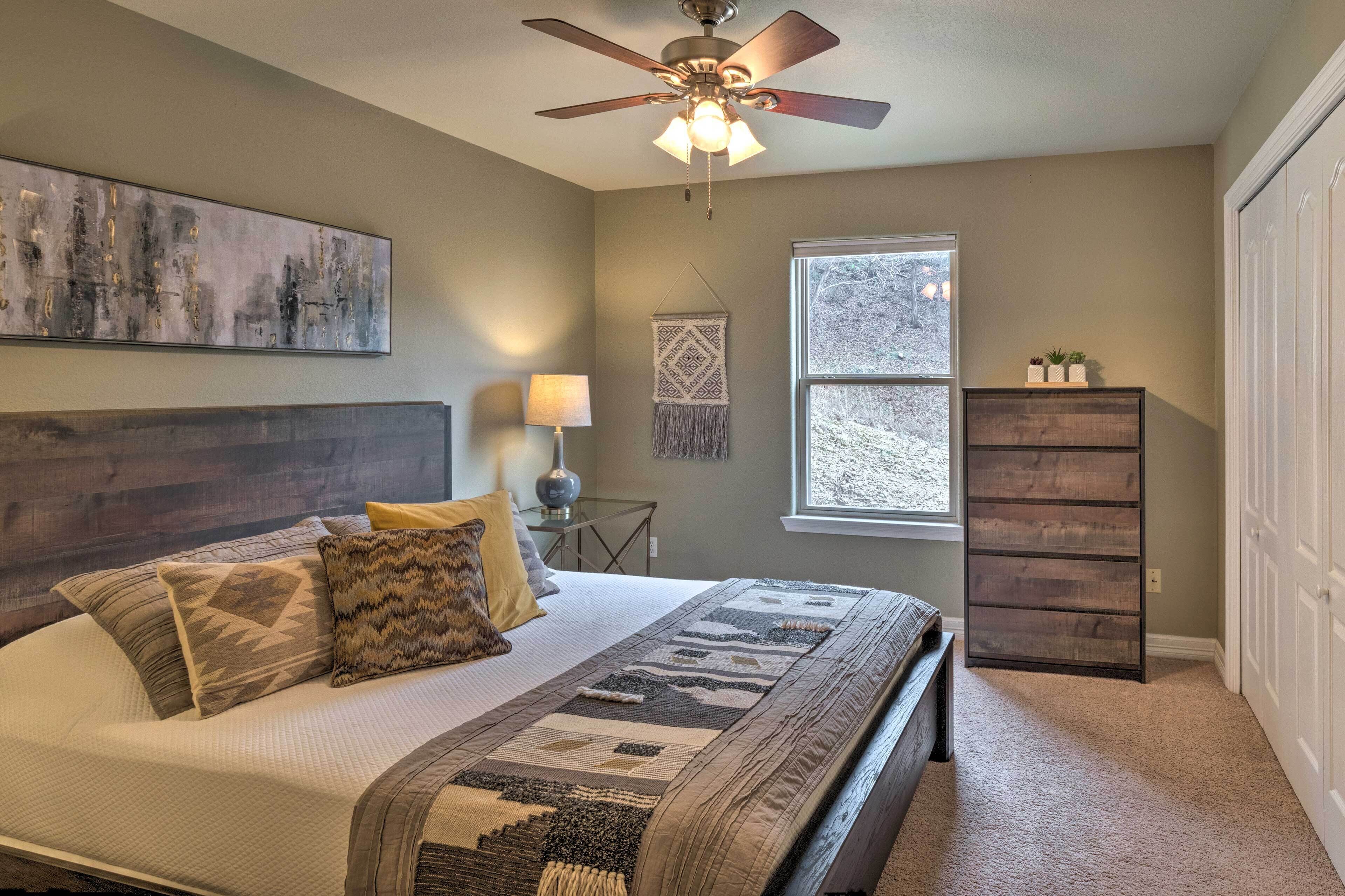 A bedroom with a bed, a ceiling fan, a window, and a dresser.