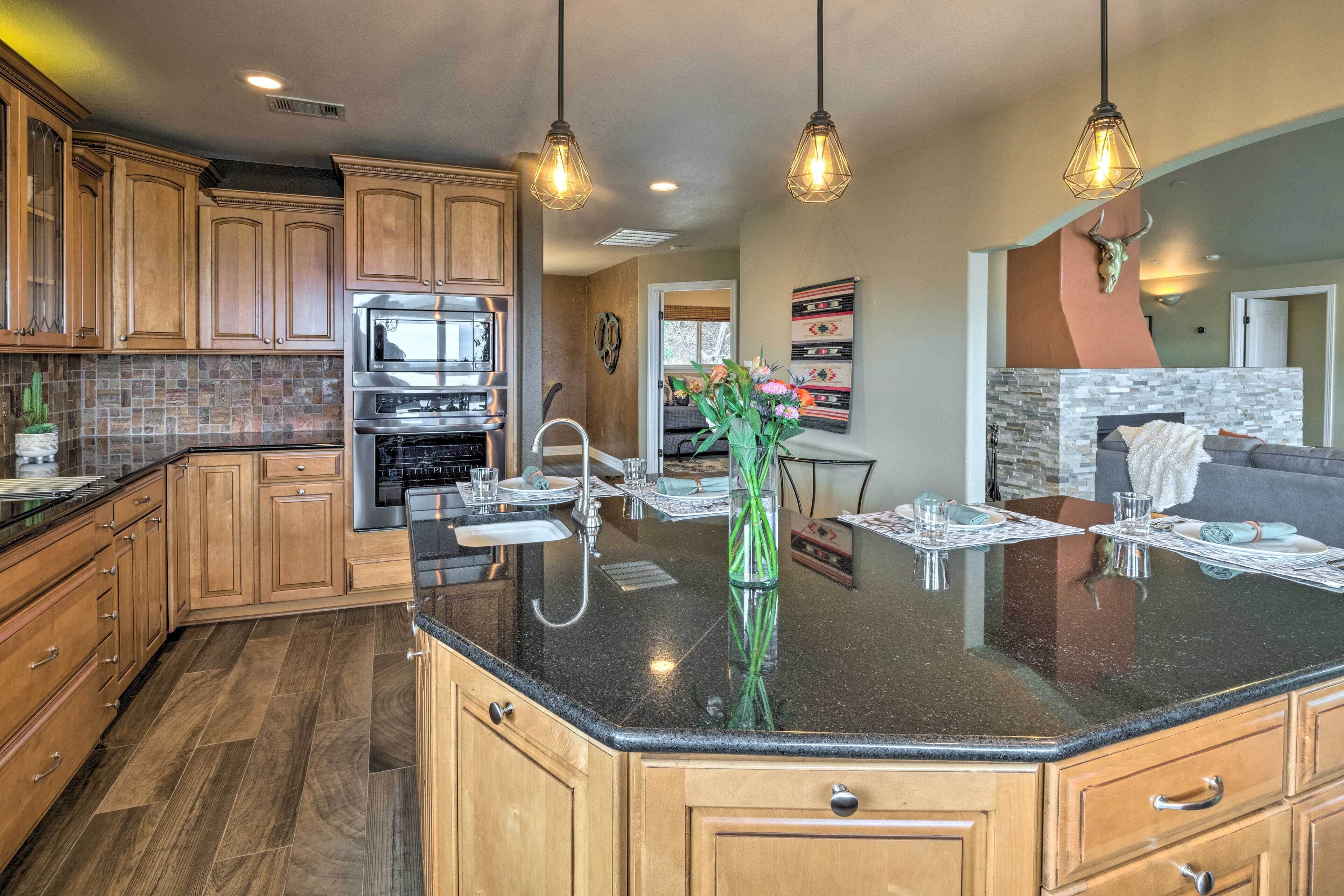 A modern kitchen with wooden cabinets, a central island, and pendant lighting.