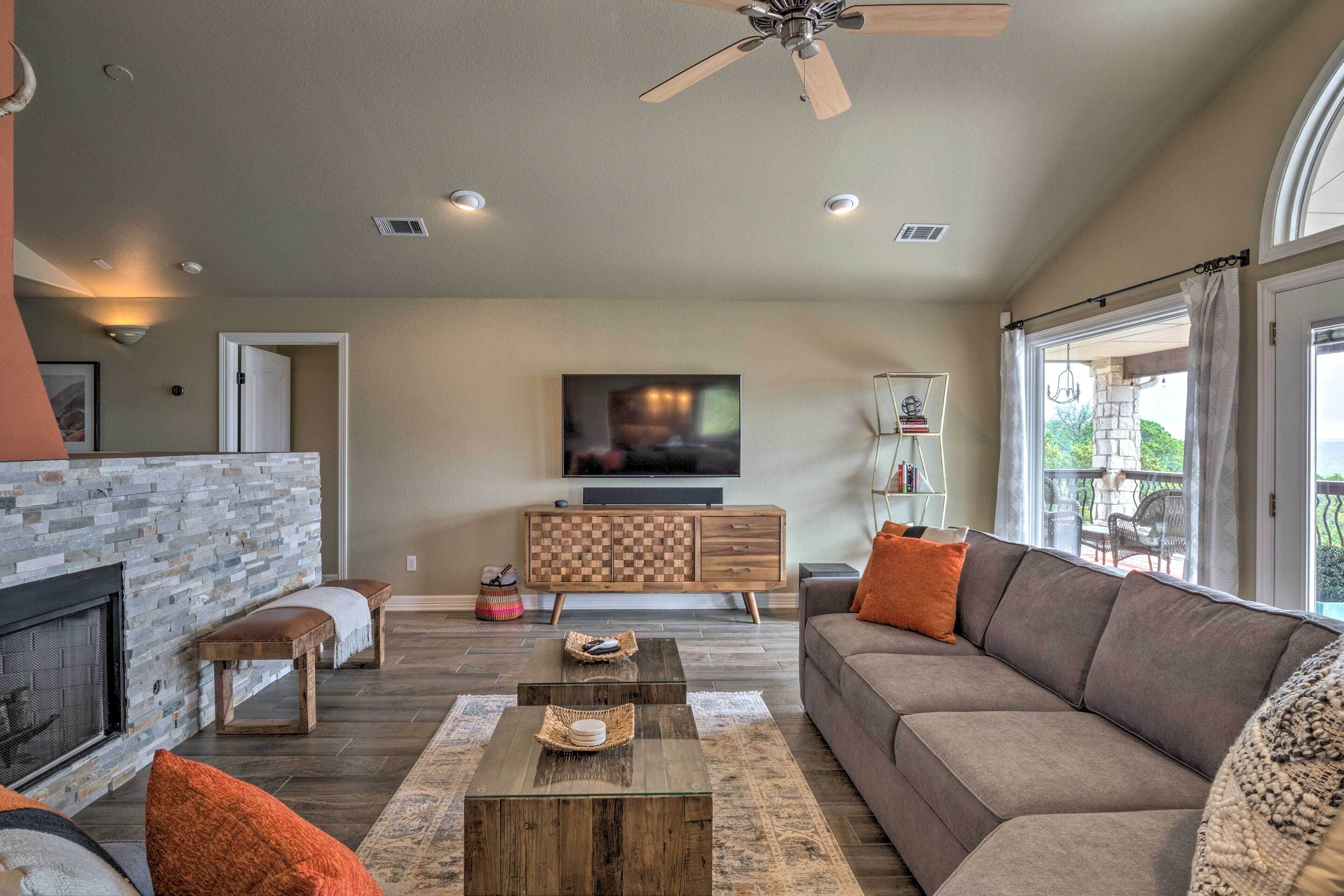 A modern living room with a stone fireplace, a large flat-screen TV, a wooden coffee table, and a comfortable sofa.