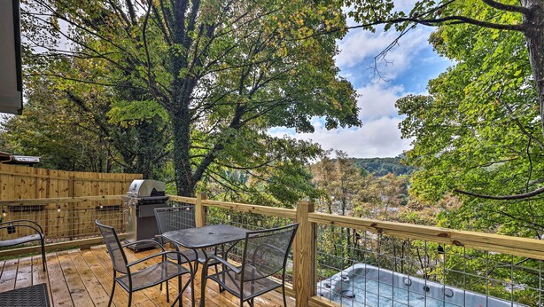 Eine Holzterrasse mit Whirlpool, Grill und Metallstühlen.