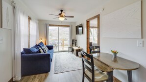 Ein modernes Wohnzimmer mit blauem Sofa, Holztisch und Deckenventilator.