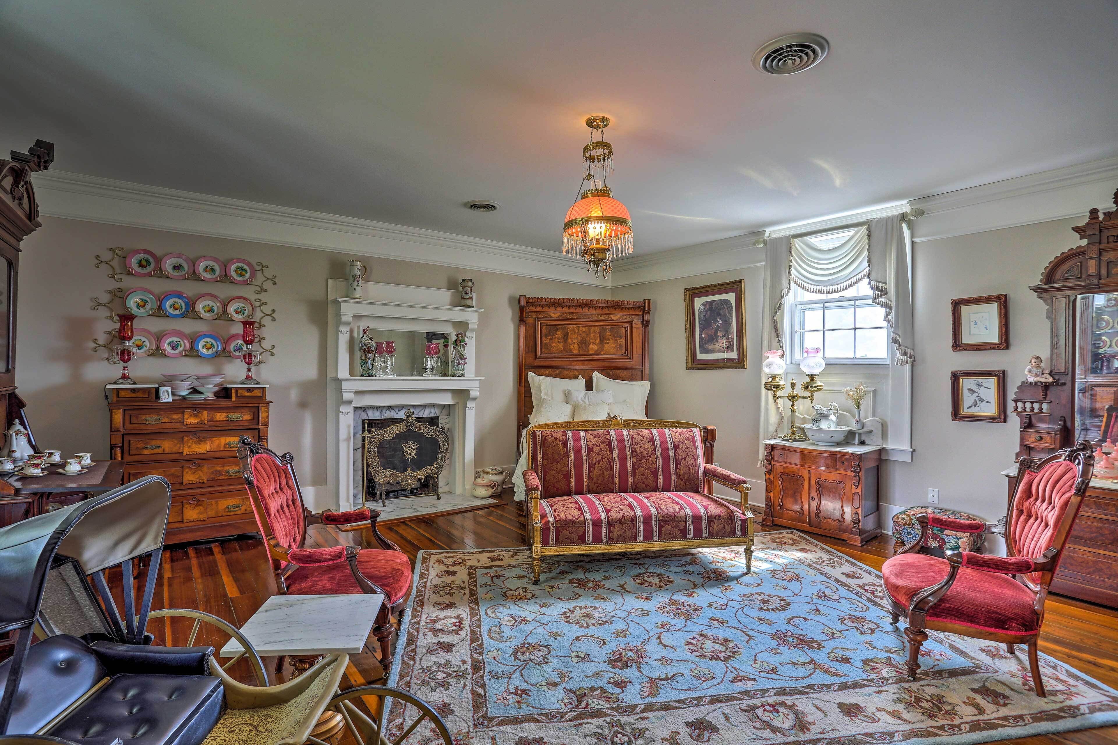 A traditional room with a fireplace, a sofa, a dining table with chairs, and a chandelier.