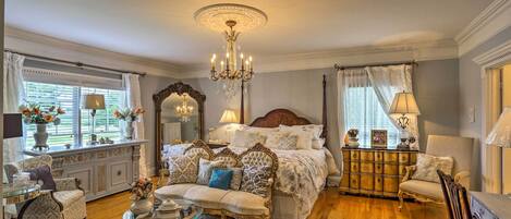 Een klassieke slaapkamer met een groot bed, sierlijk meubilair en een kroonluchter.