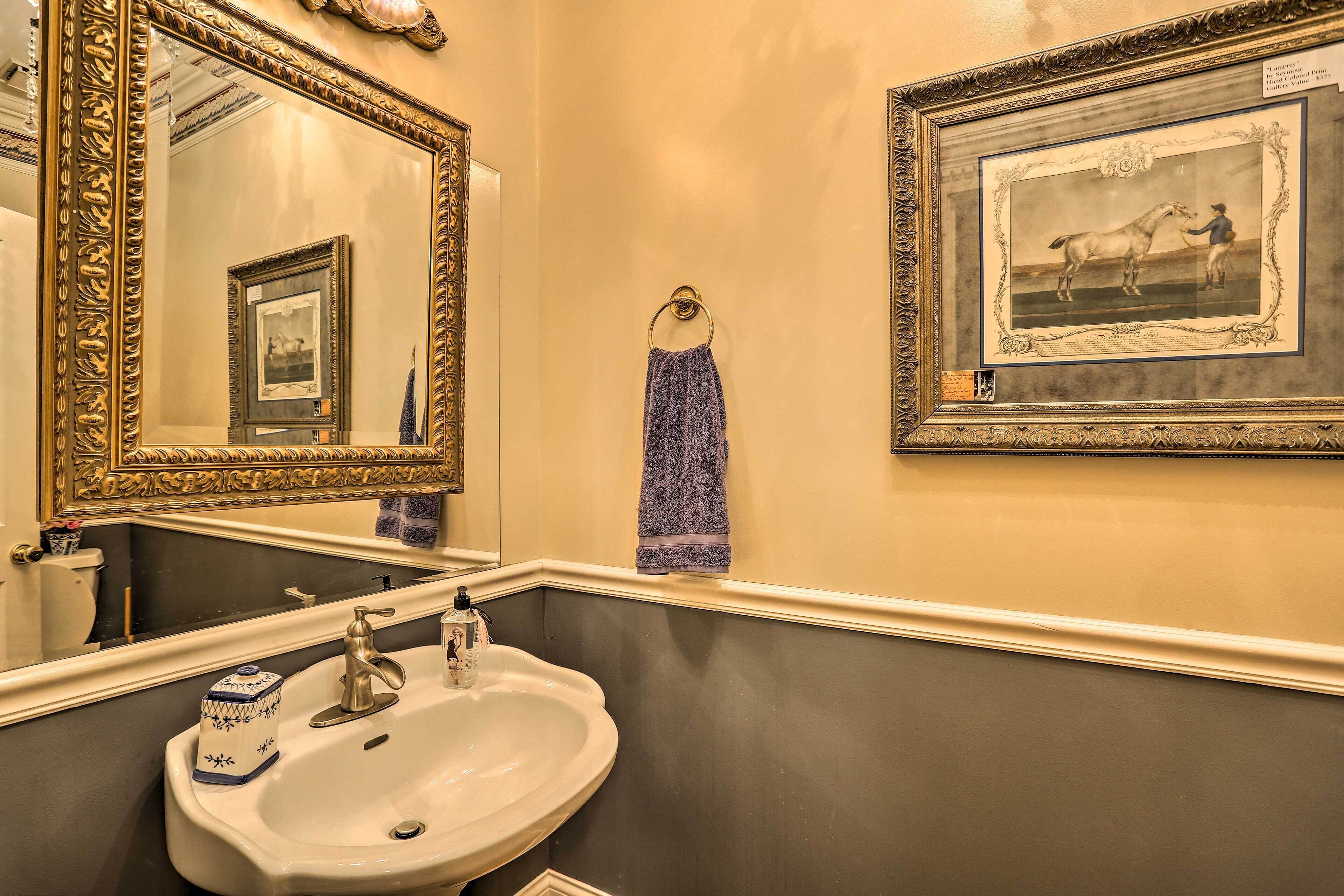 A bathroom with a large mirror, a sink, and a framed picture on the wall.