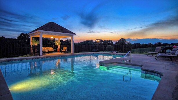 Una piscina con zona cubierta y sillones de descanso.