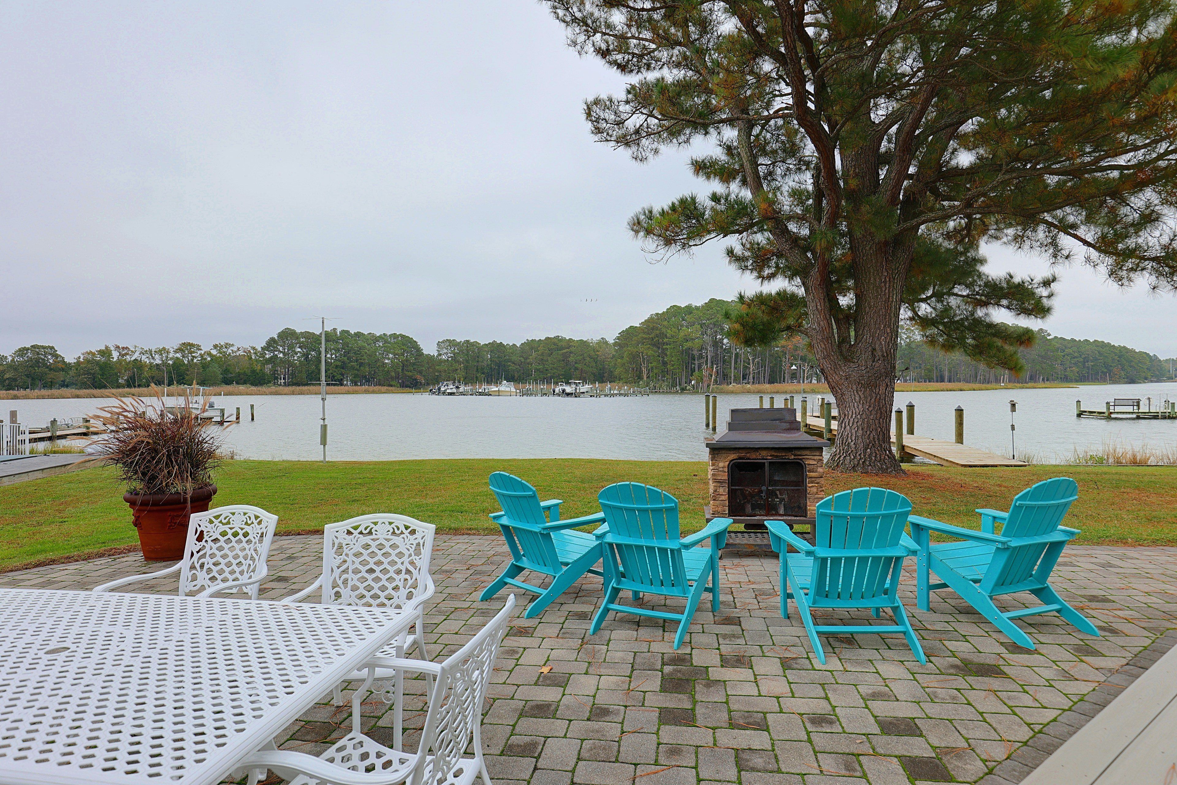 A patio with outdoor seating, a grill, and a view of a lake.