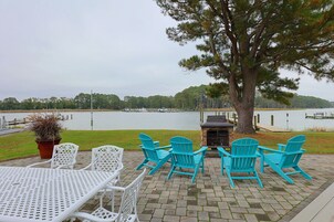 A patio with outdoor seating, a grill, and a view of a lake.