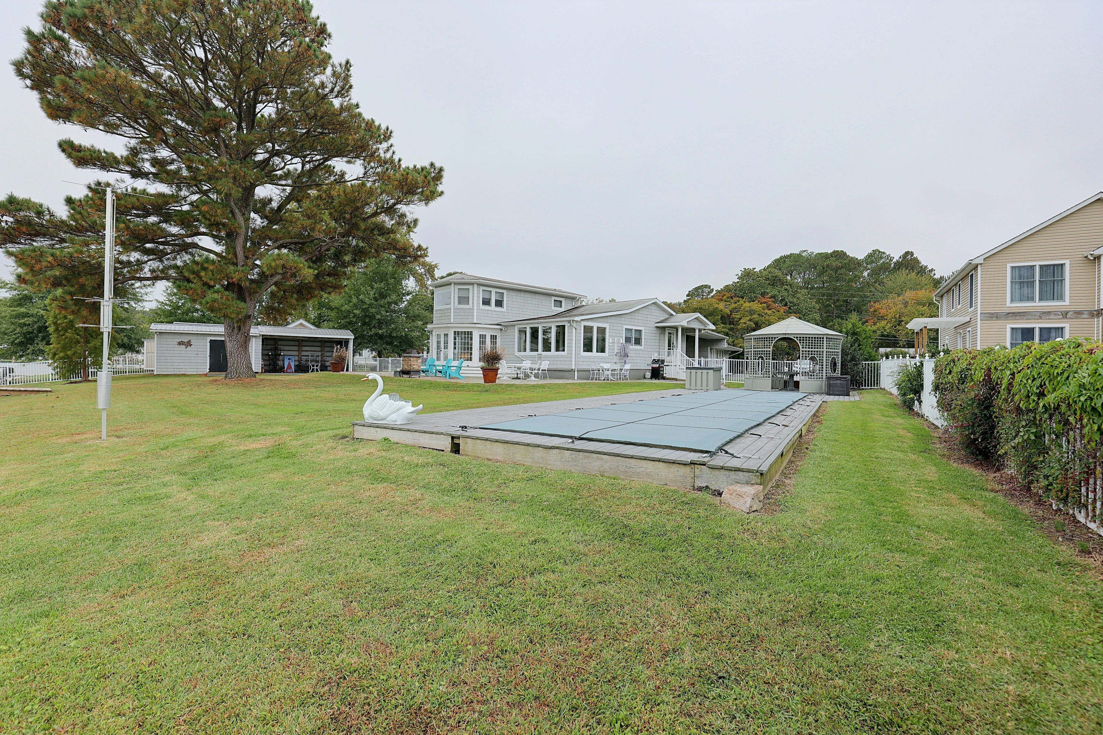 A residential area with a large lawn, a gazebo, and a swimming pool.