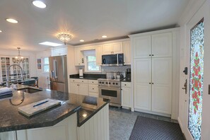 A modern kitchen with white cabinetry, stainless steel appliances, and a granite countertop. - Grasonville Home w/ Private Pool on the Water (Grasonville)