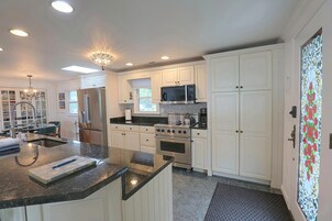 A modern kitchen with white cabinetry, stainless steel appliances, and a granite countertop.