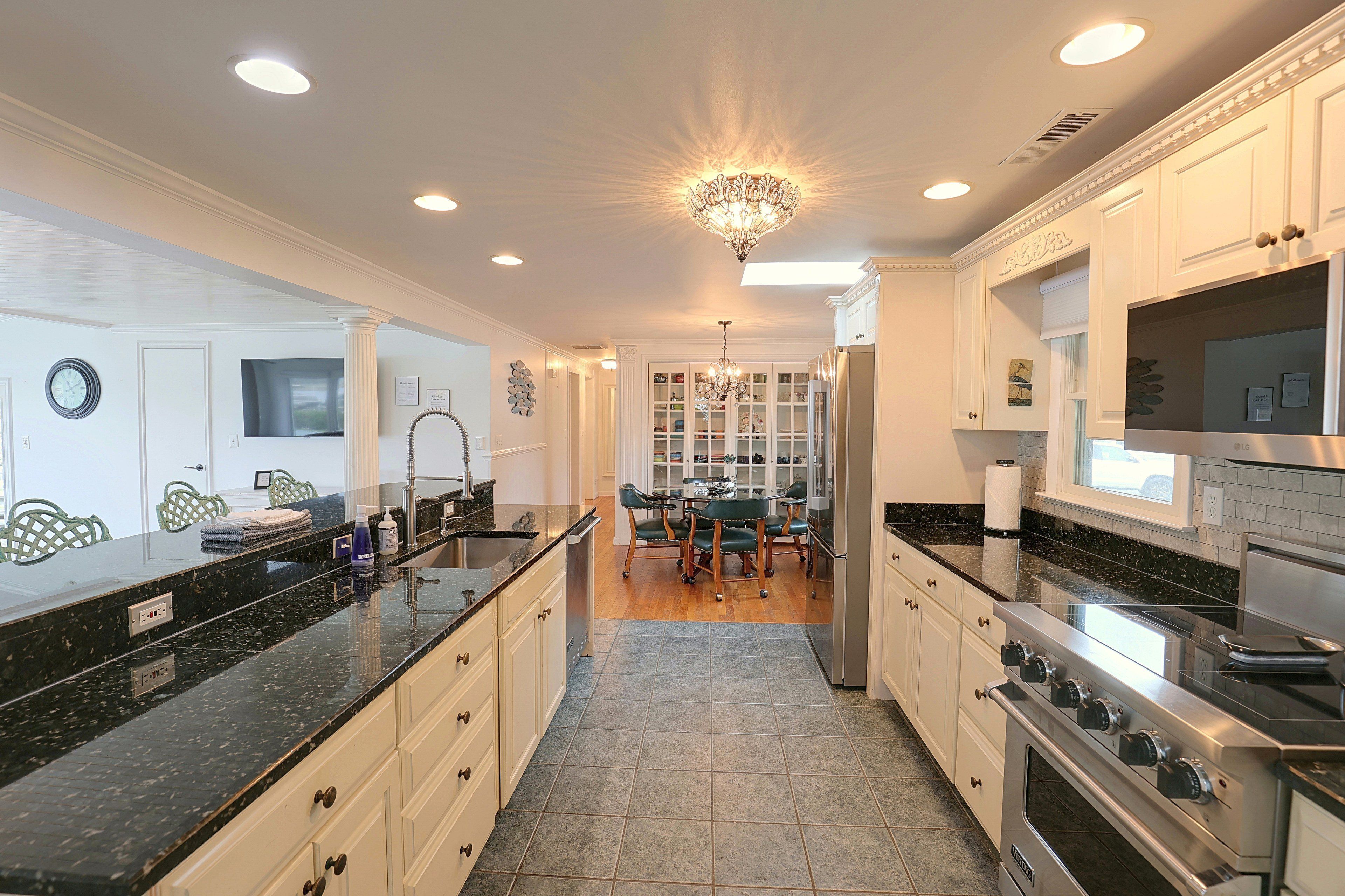 A modern kitchen with a central island, built-in appliances, and a dining area with a chandelier.