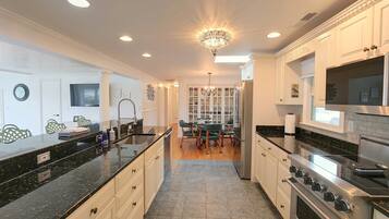 A modern kitchen with a central island, built-in appliances, and a dining area with a chandelier.