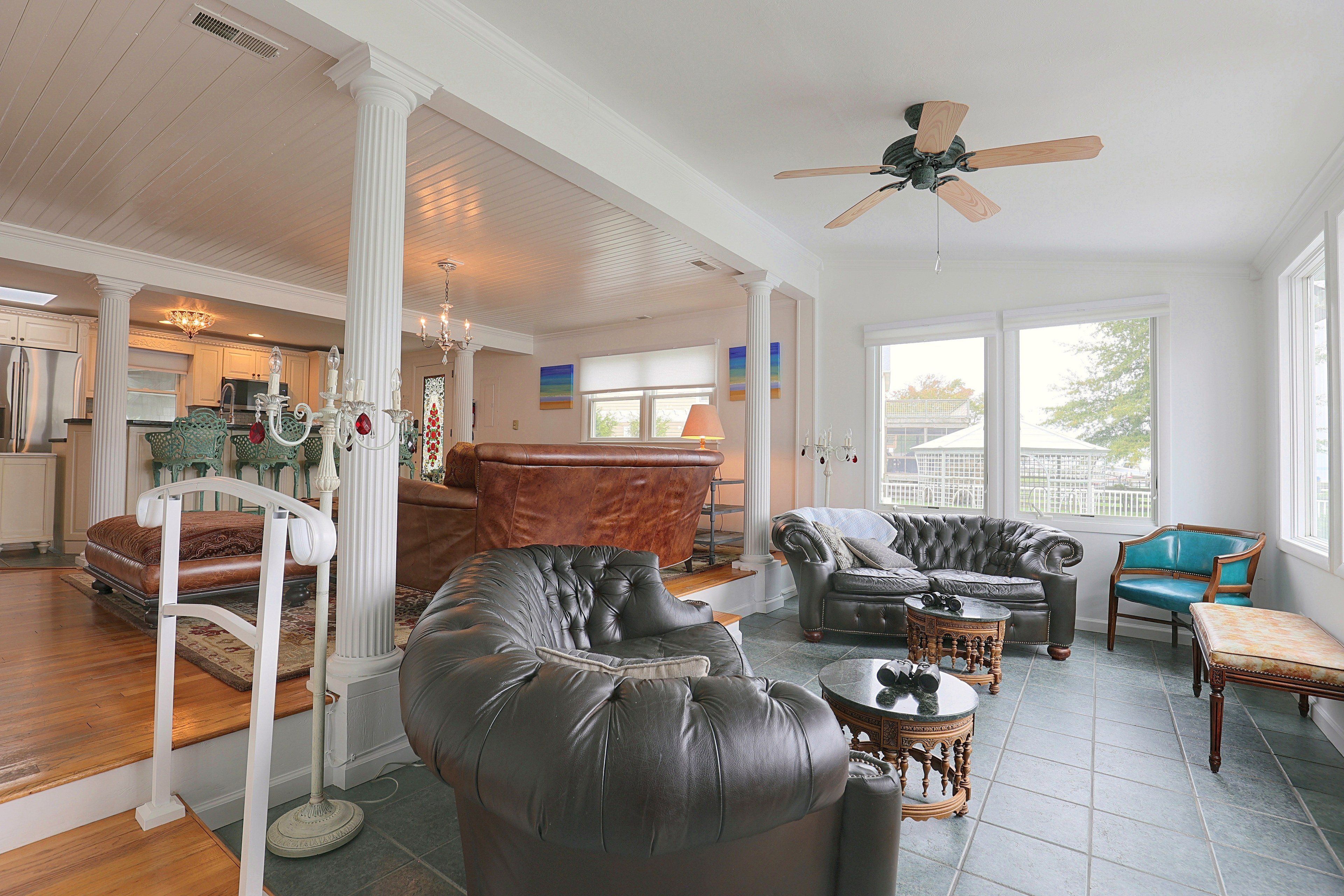 A spacious living area with a high ceiling, a ceiling fan, and a view of the outside through large windows.