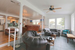 A spacious living area with a high ceiling, a ceiling fan, and a view of the outside through large windows.