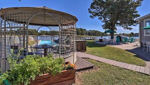 Um gazebo com mesa de bilhar e cadeiras, cercado por um deck de madeira e uma grande árvore.