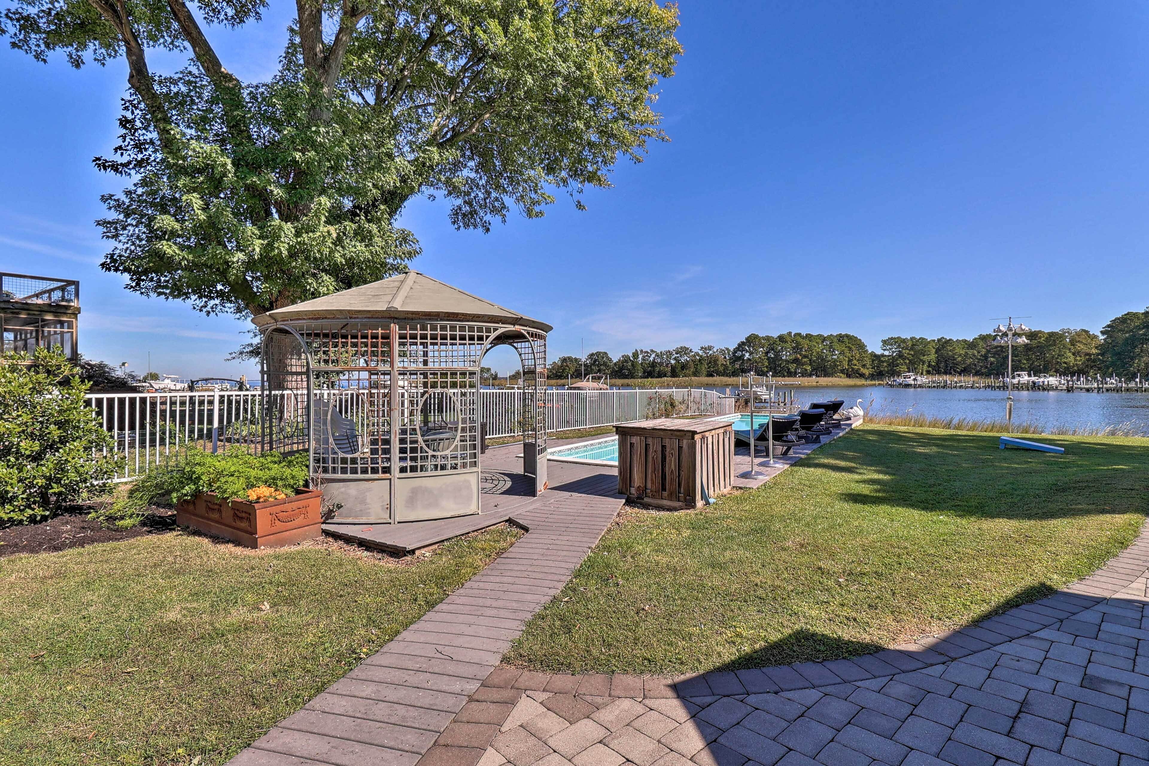 A gazebo with a metal fence, a pool, and a grassy area with a pathway.