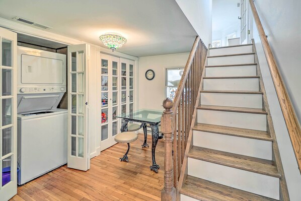 A kitchen with a built-in washer and dryer, a glass-top table, and a staircase with wooden railings.