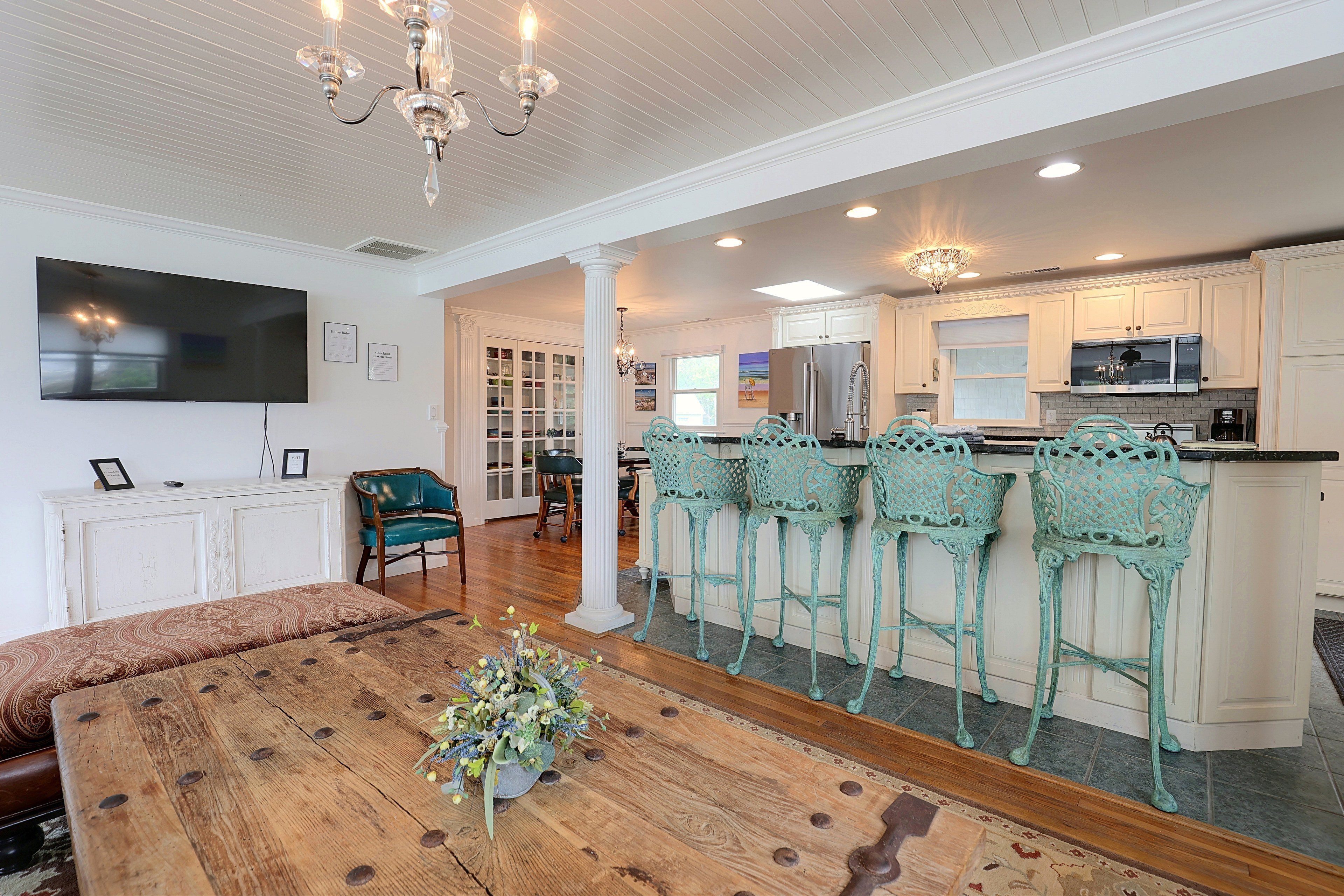 A spacious living area with a wooden dining table, a television, and a chandelier.