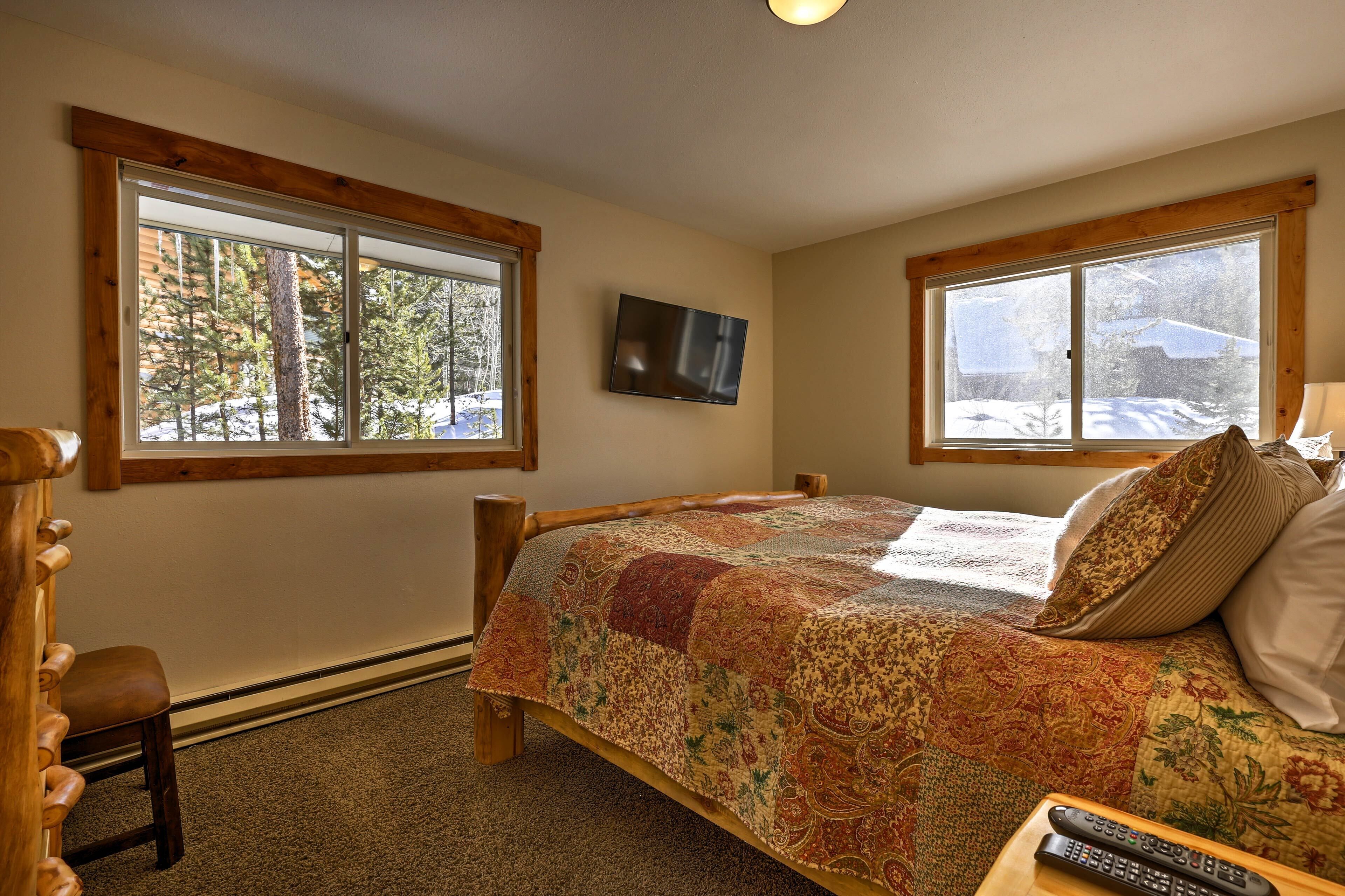 A bedroom with a bed, a TV, and large windows.