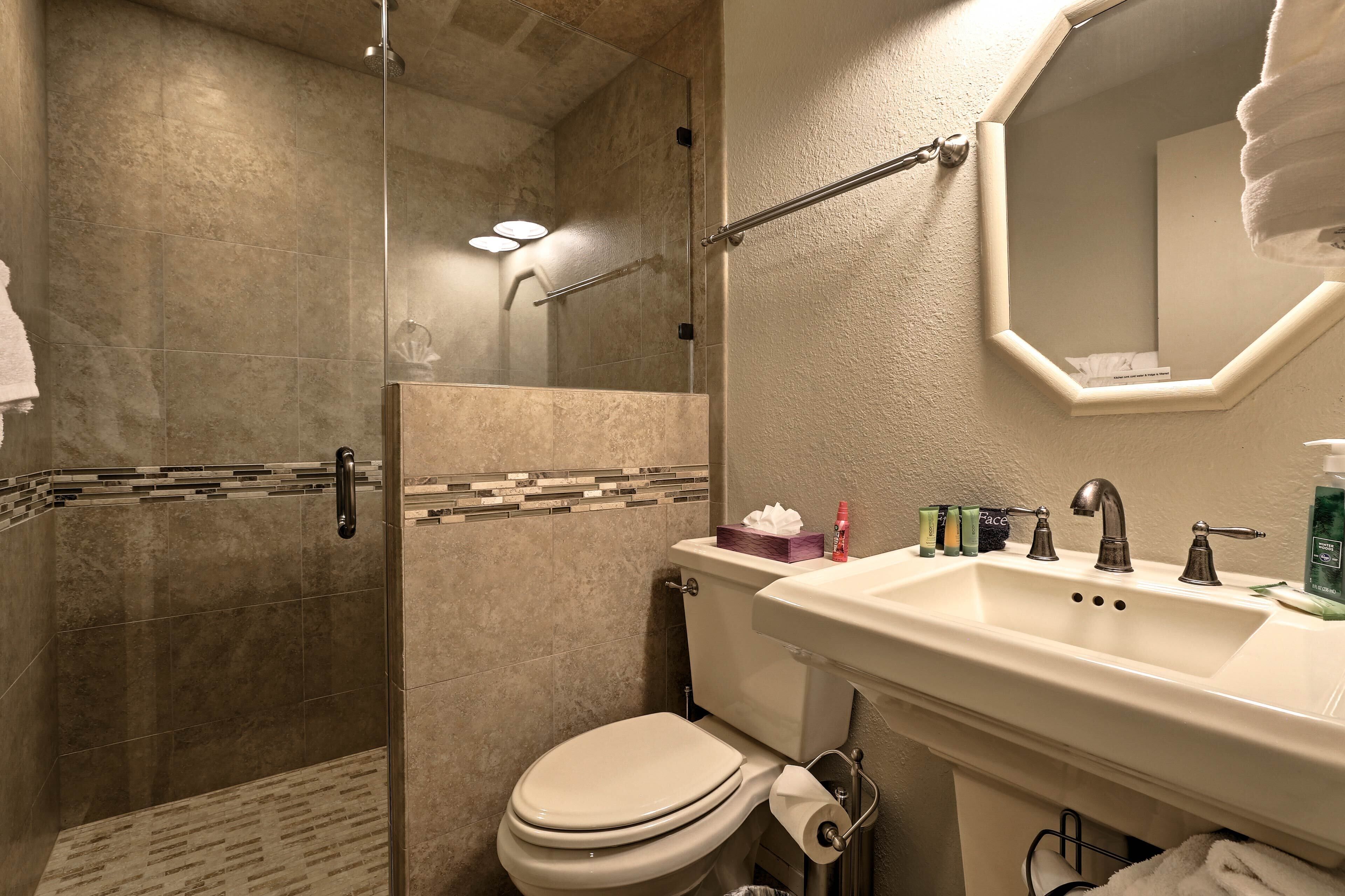 Een badkamer met douche, toilet en wastafel.